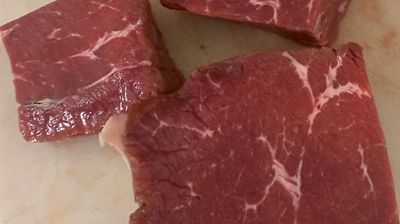 Raw beef cuts displayed on a cutting board, showcasing marbling and texture, ideal for cooking or meal preparation.